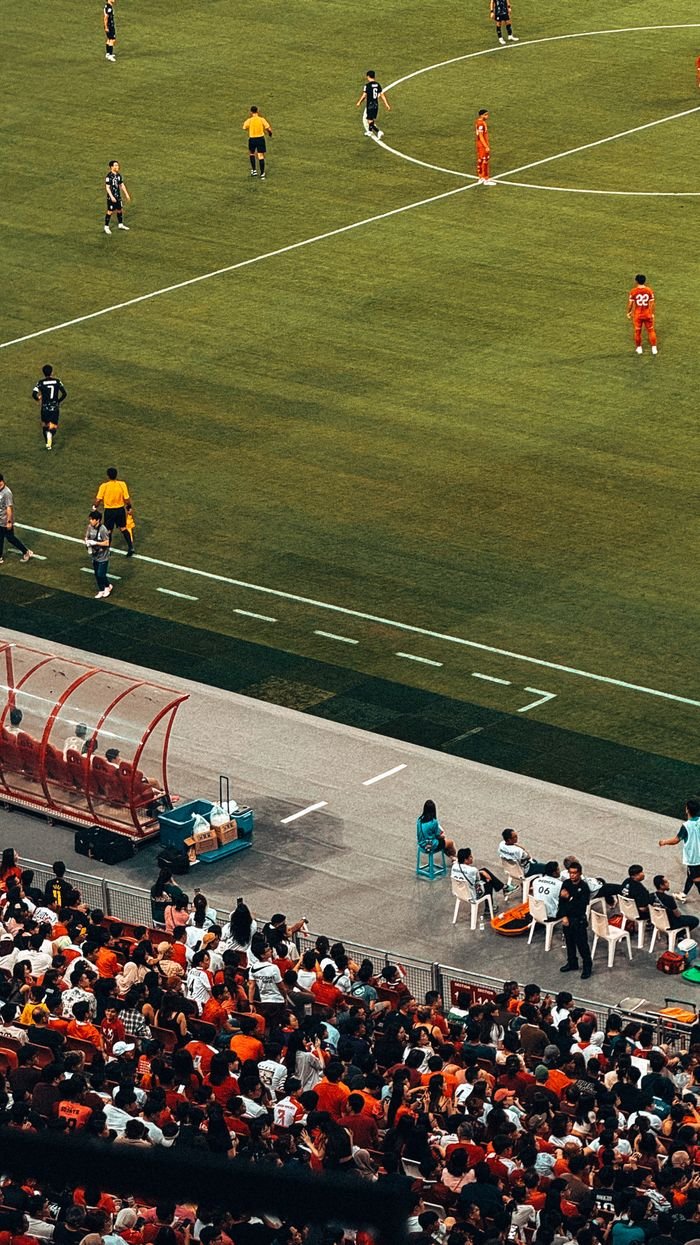 High-angle view of a vibrant soccer match capturing players and fans at Singapore stadium.