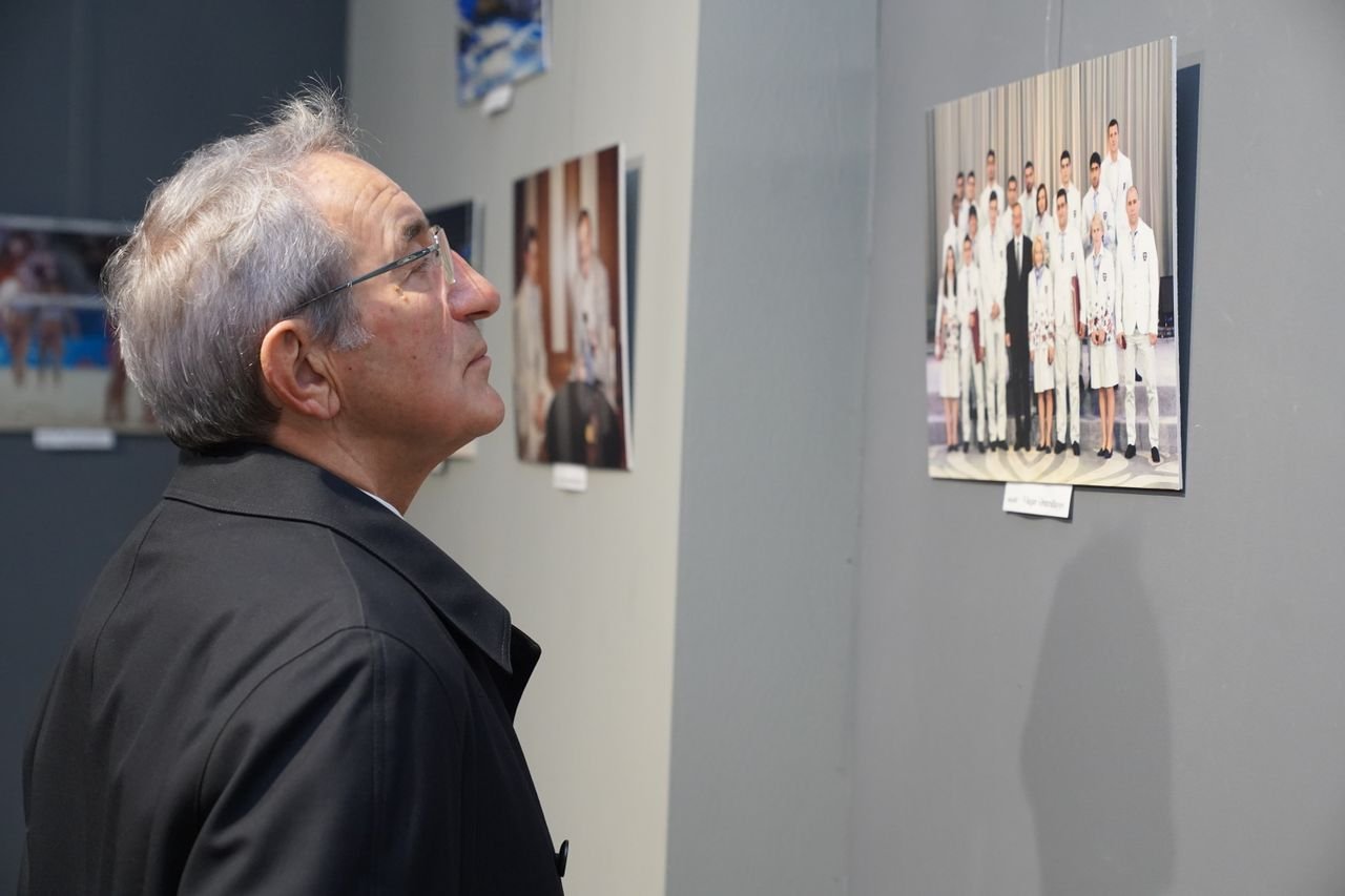 Senior man viewing photographs in an indoor art gallery exhibit.